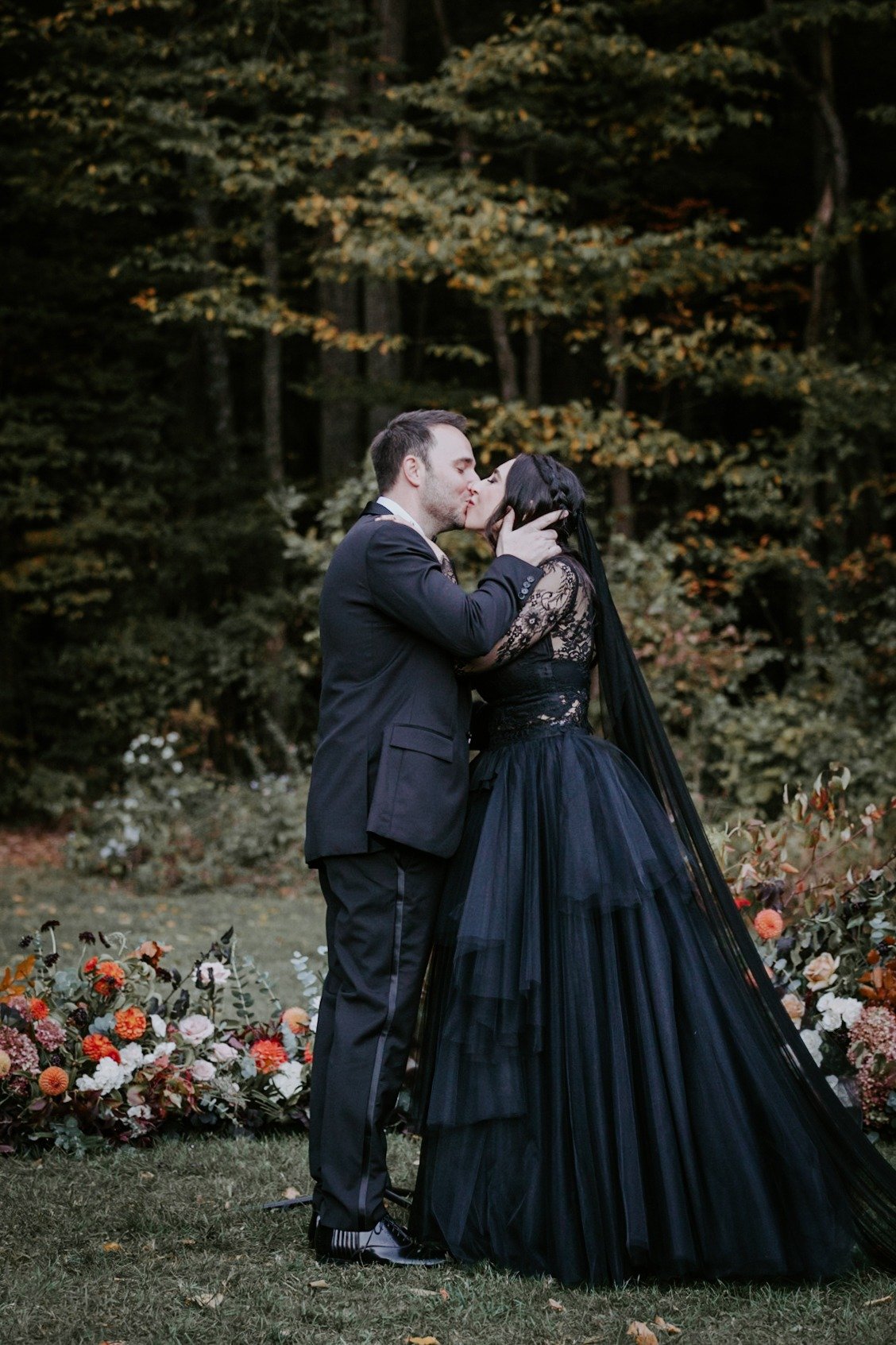 Romantic first kiss at moody goth wedding ceremony 