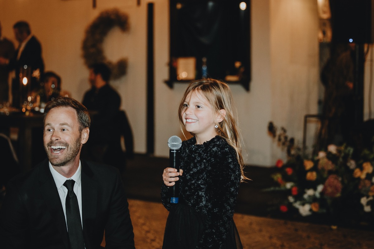 Little girl giving toast to bride and groom at tented reception