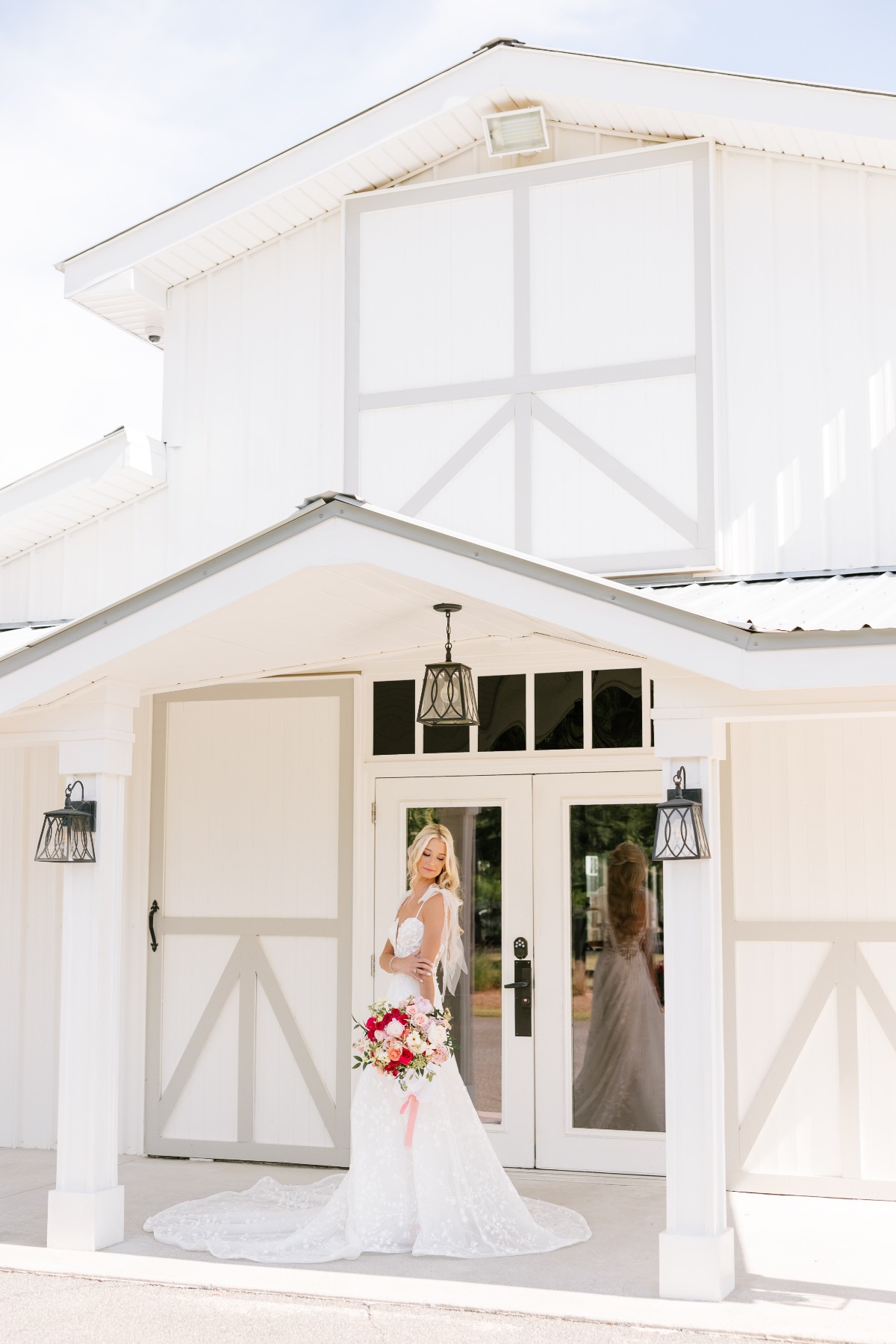 Glamorous Georgia bride in floral gown in front of white barn 