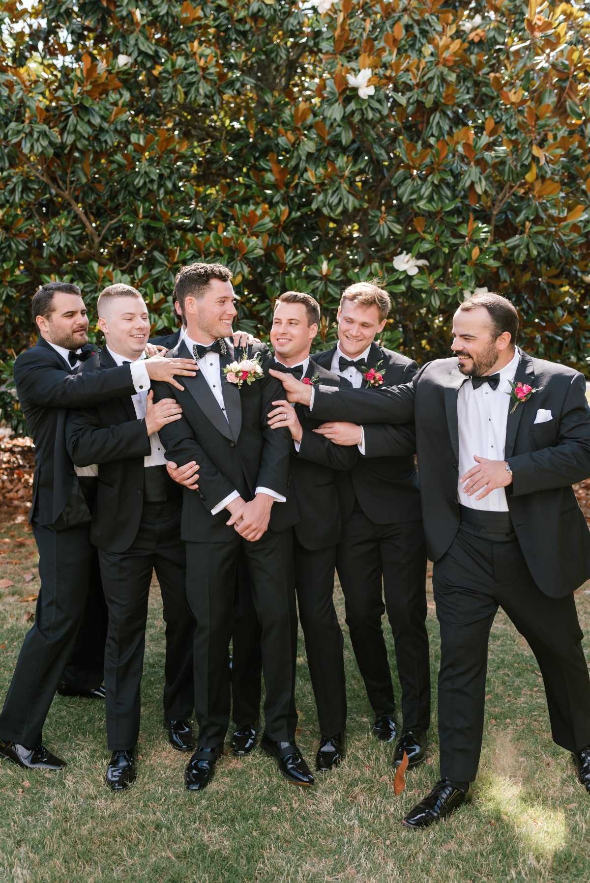 Classic groomsmen in black tuxedos with pink boutonnieres 