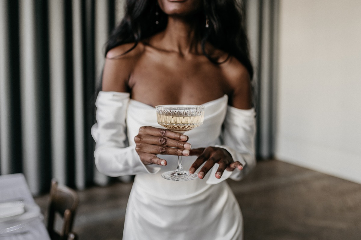 Bride holding champagne goblet at moody indoor wedding 