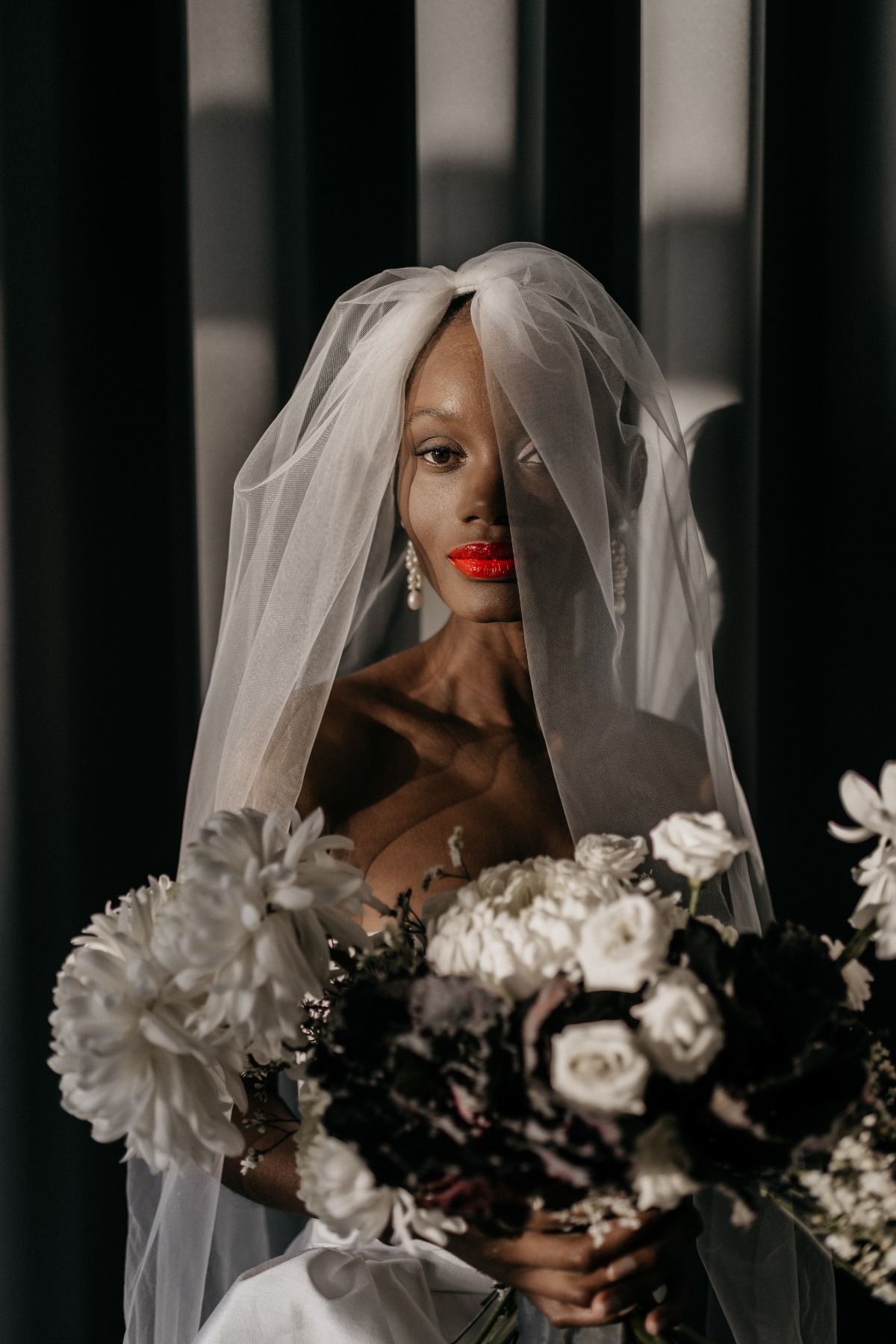 Glowing veiled Black bride in red lipstick with bouquet