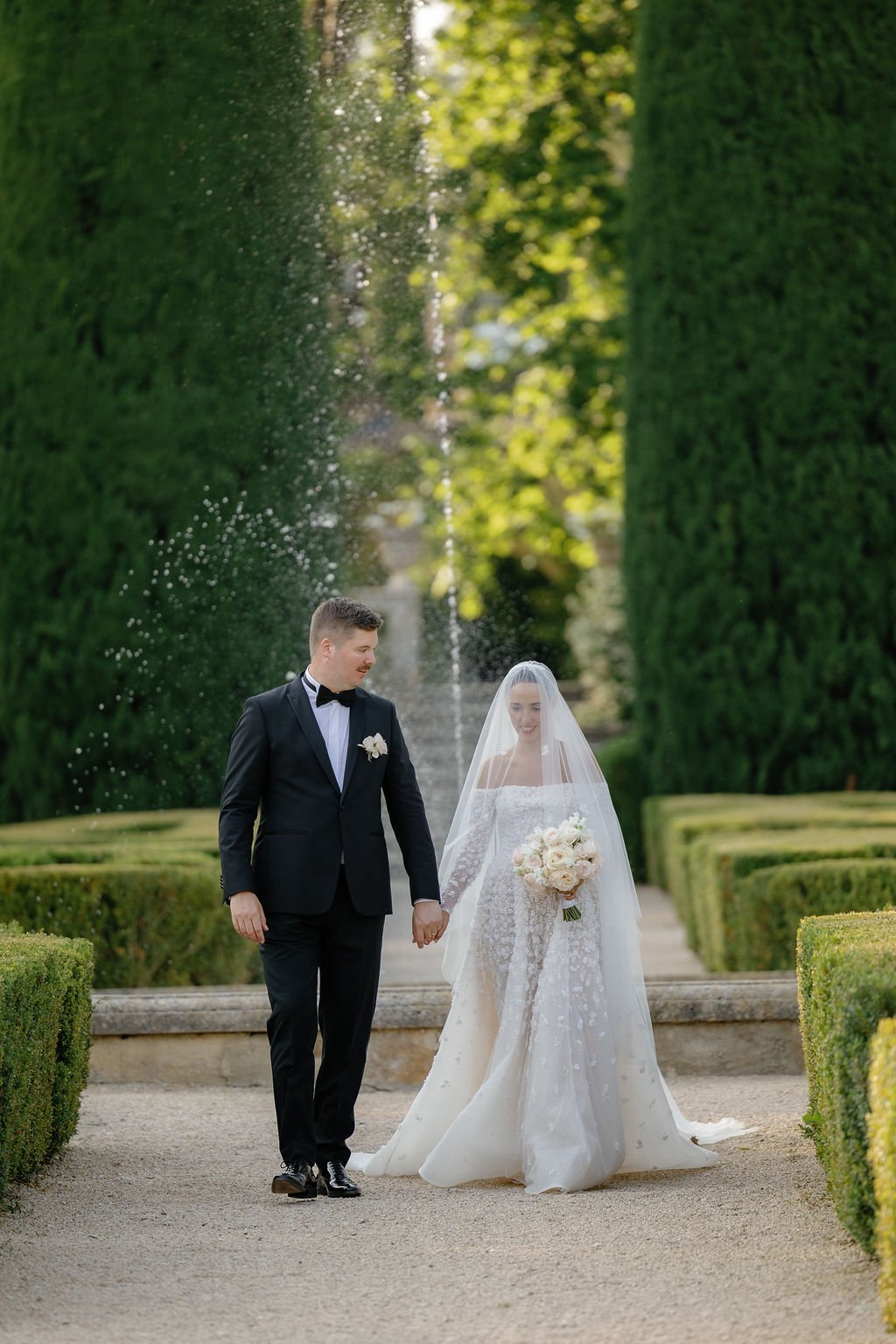 Newlyweds walk French chateau gardens at destination wedding