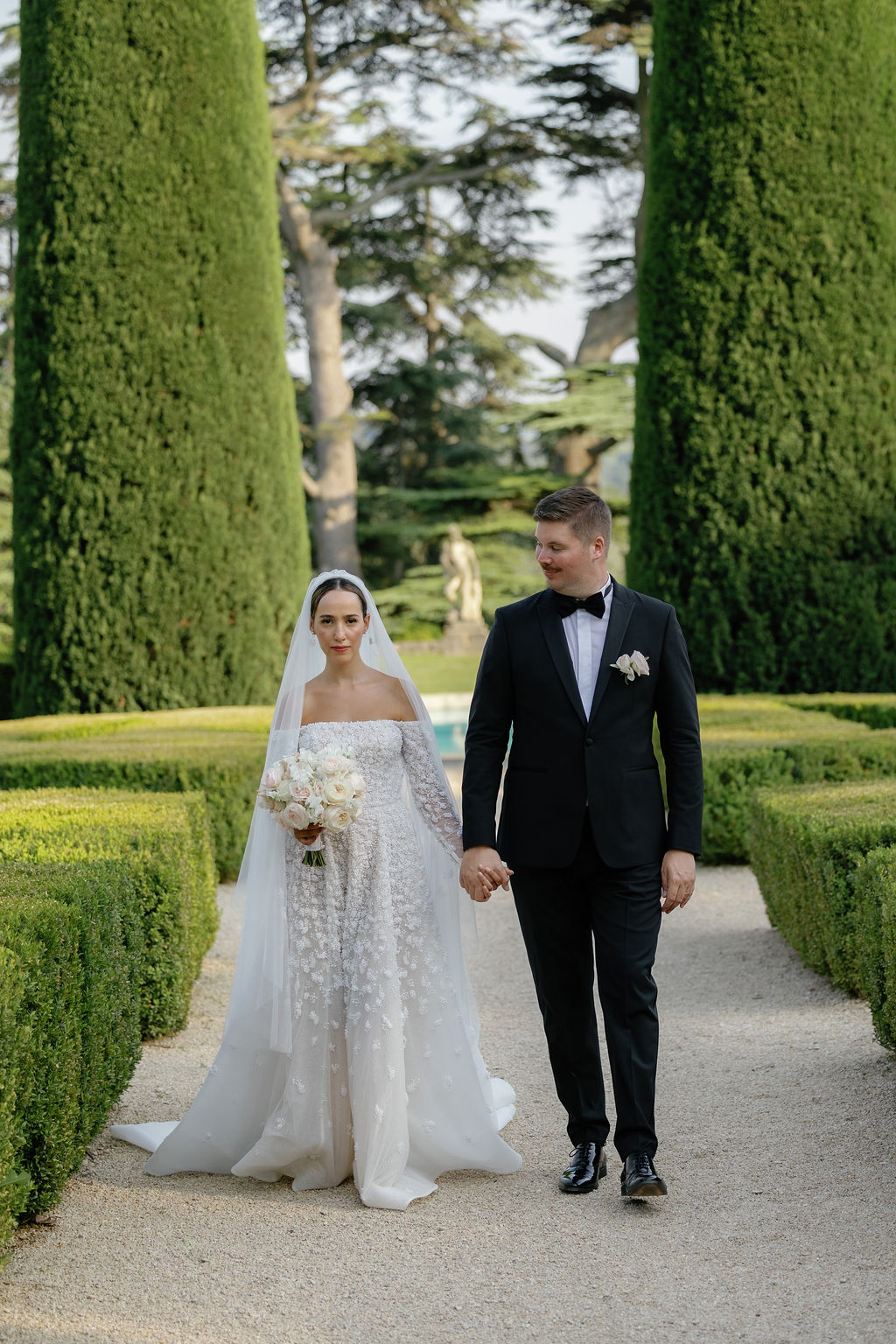 Newlyweds walk luxurious chateau gardens at French wedding