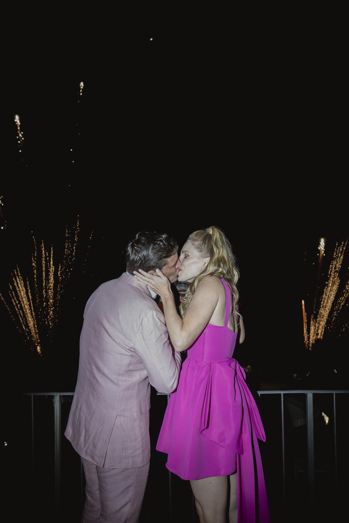 Bride and groom kissing at fireworks display 