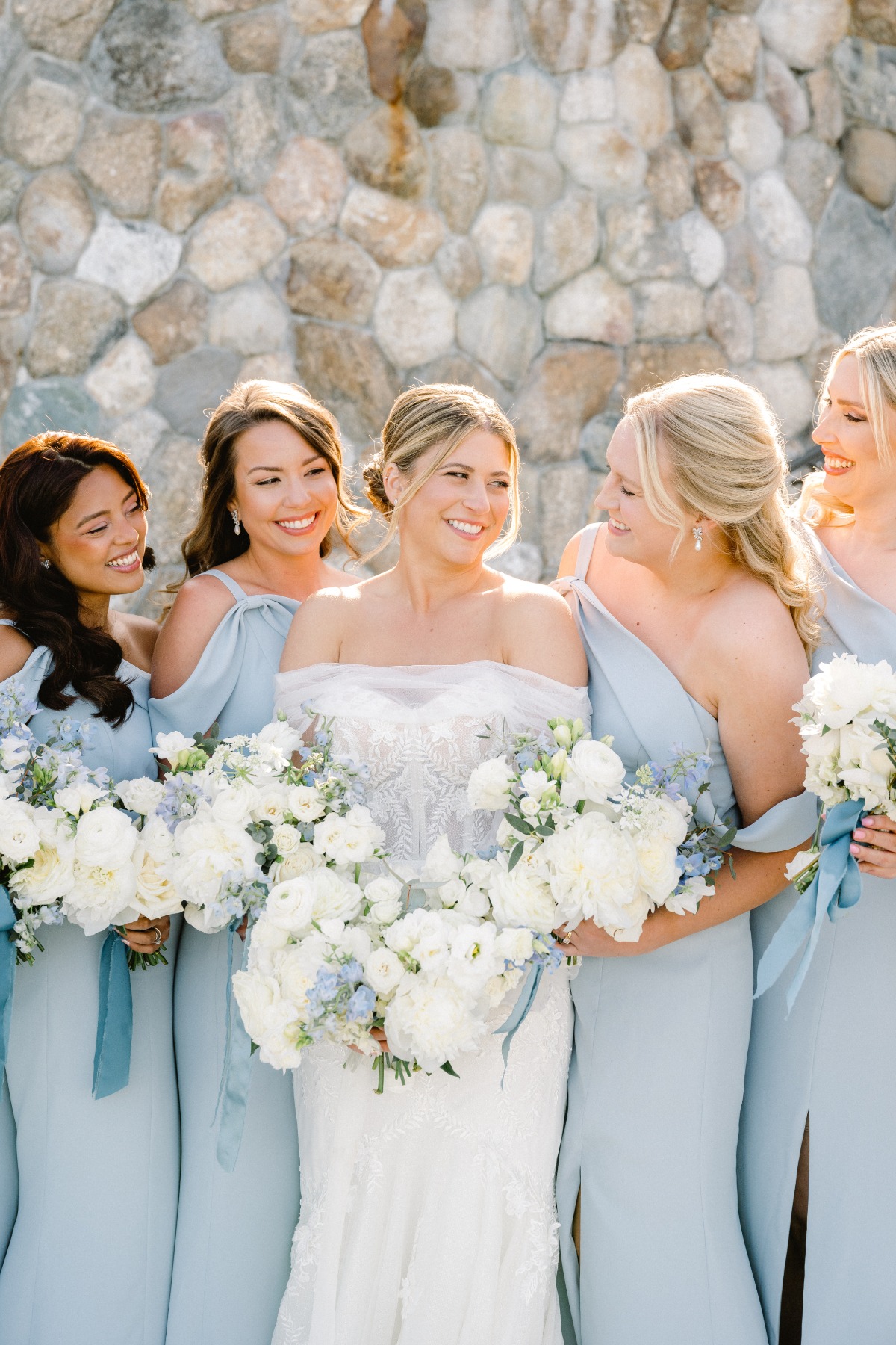 Bride in ornate lace gown with pastel blue bridesmaids 