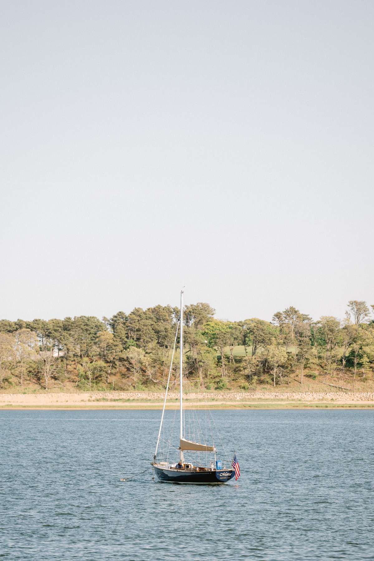 Sailboats sailing by coastal wedding ceremony in Cape Cod