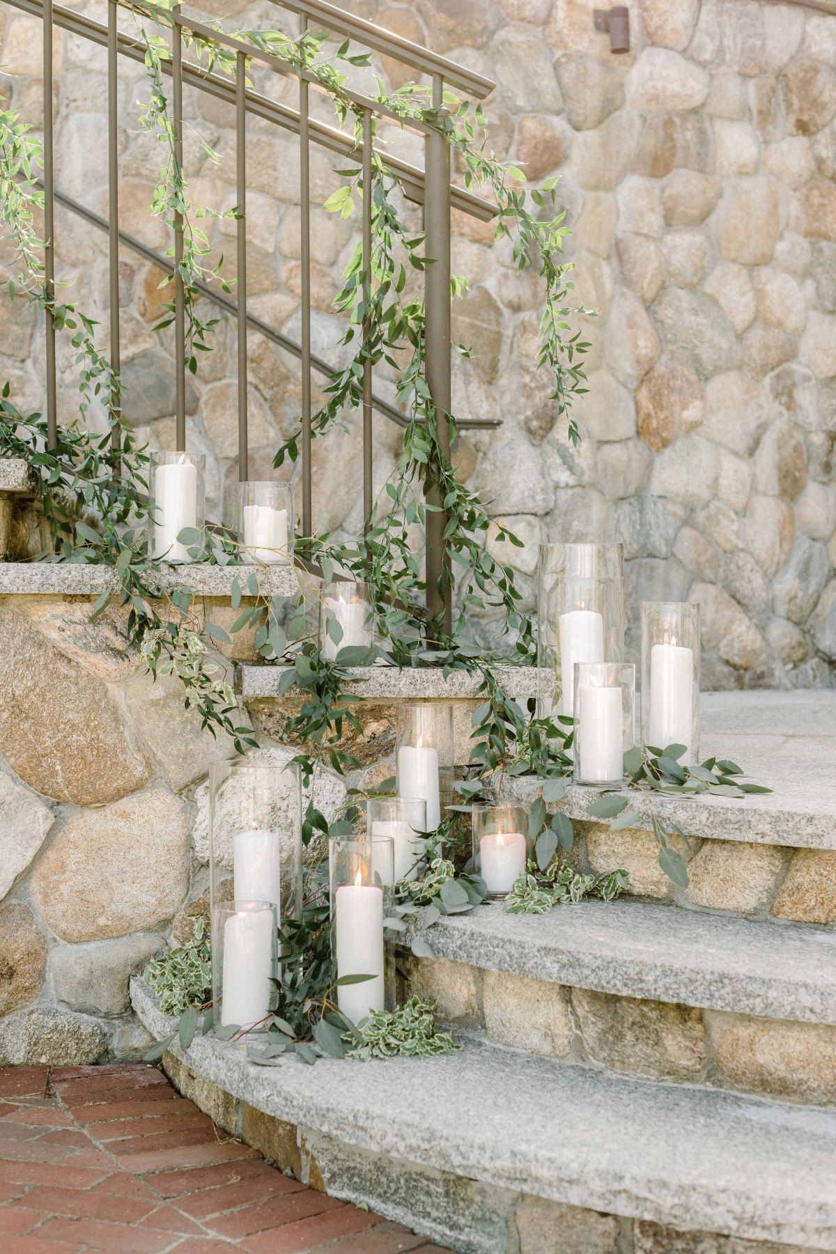 Elegant white taper candles with greenery up wedding stairs