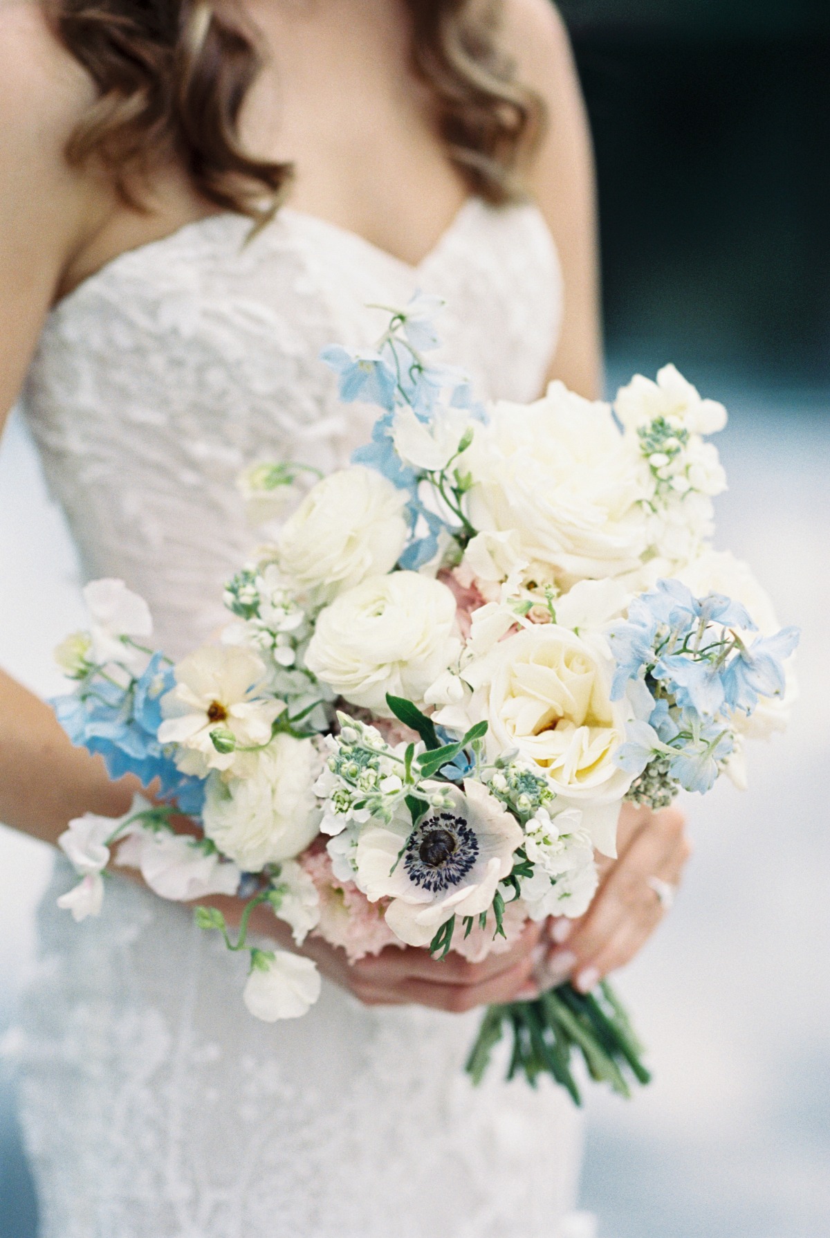 White bridal bouquet with pops of pastel blue larkspur
