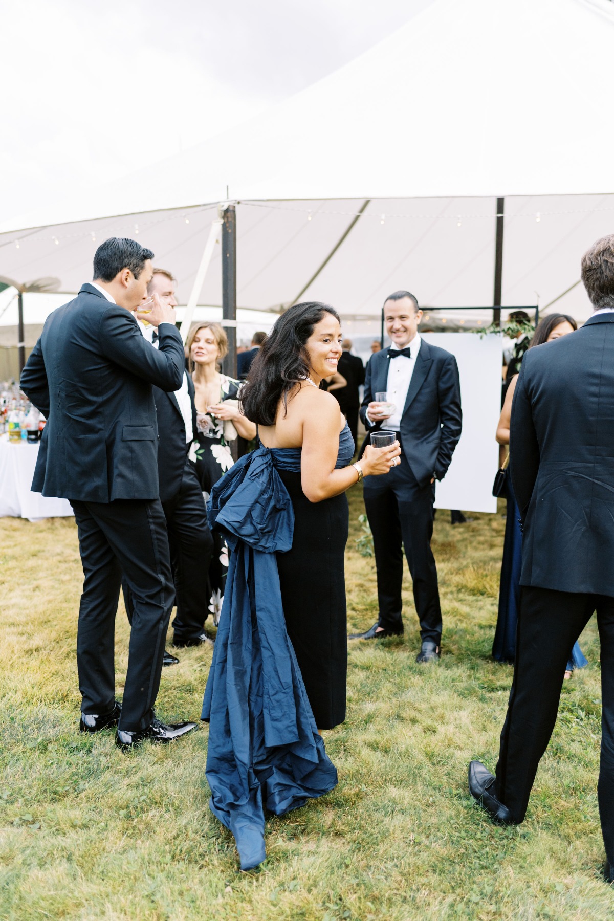 Wedding guest in dark blue dress with oversized bow 