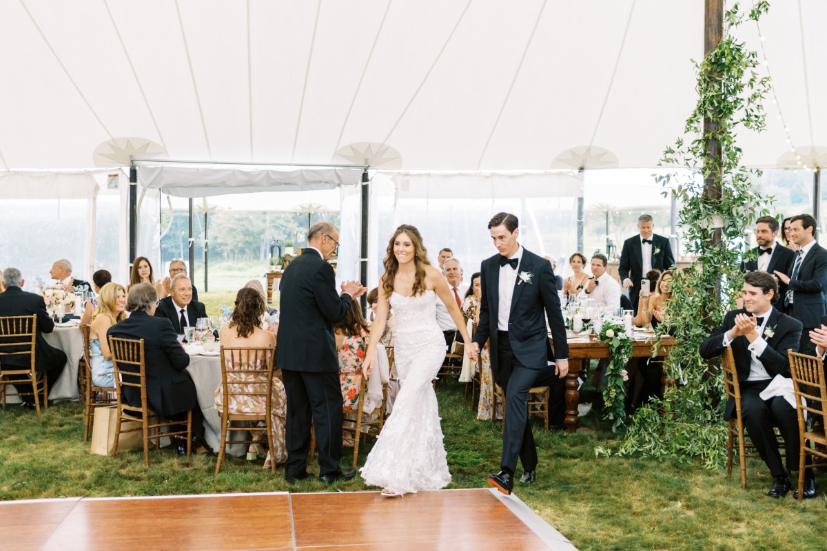 Grand entrance into greenery filled reception tent 