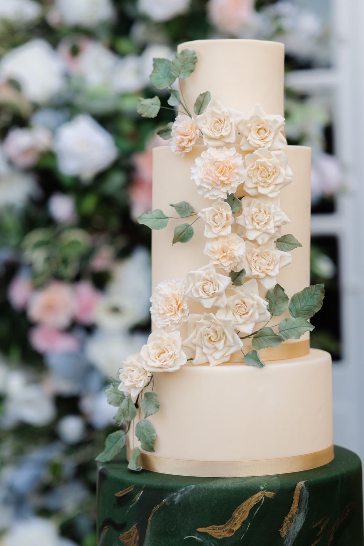 Warm sand and emerald green colored wedding cake with flowers