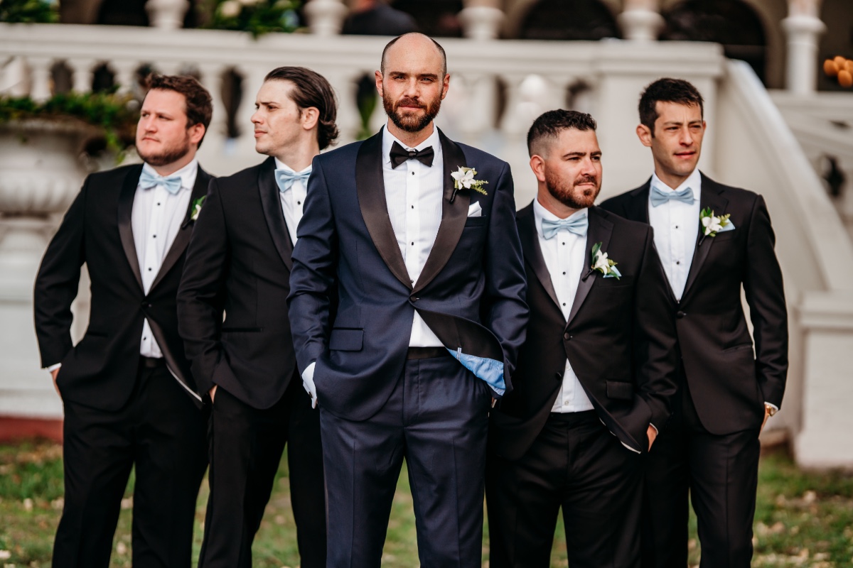groomsmen in black tuxes with blue bow ties