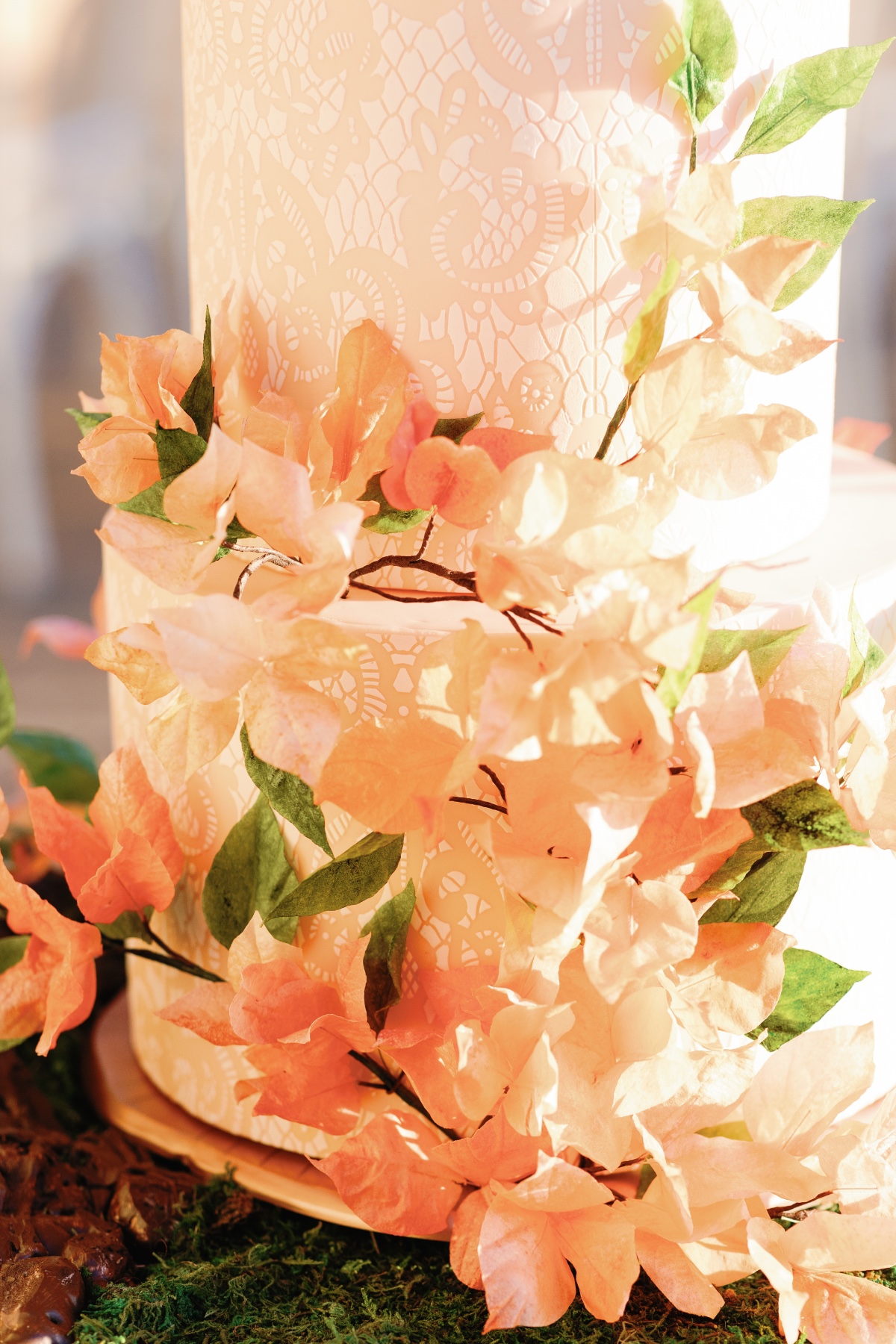 Peach and green flower covered wedding cake with lace texture