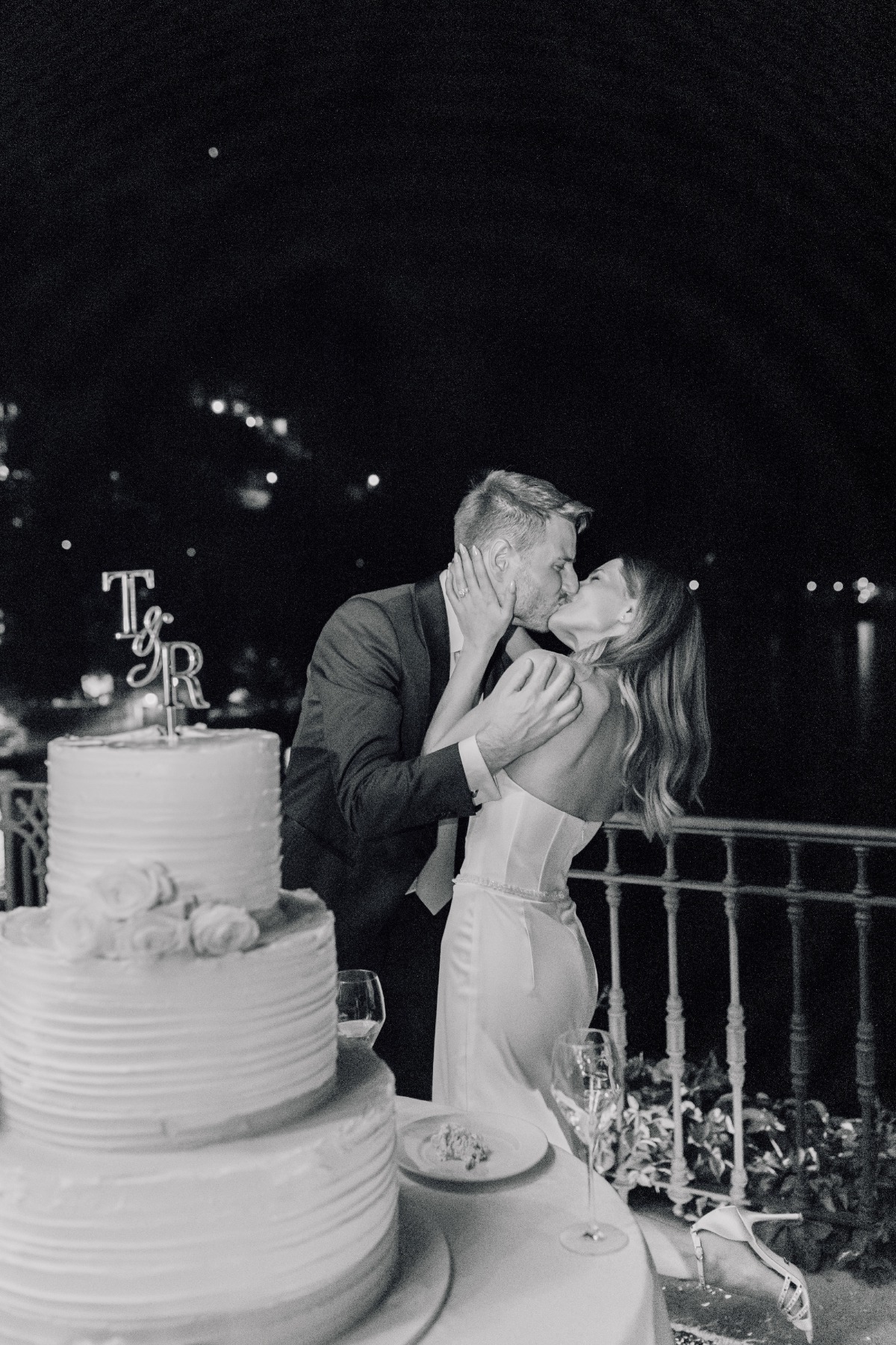bride and groom kiss by wedding cake on lake como