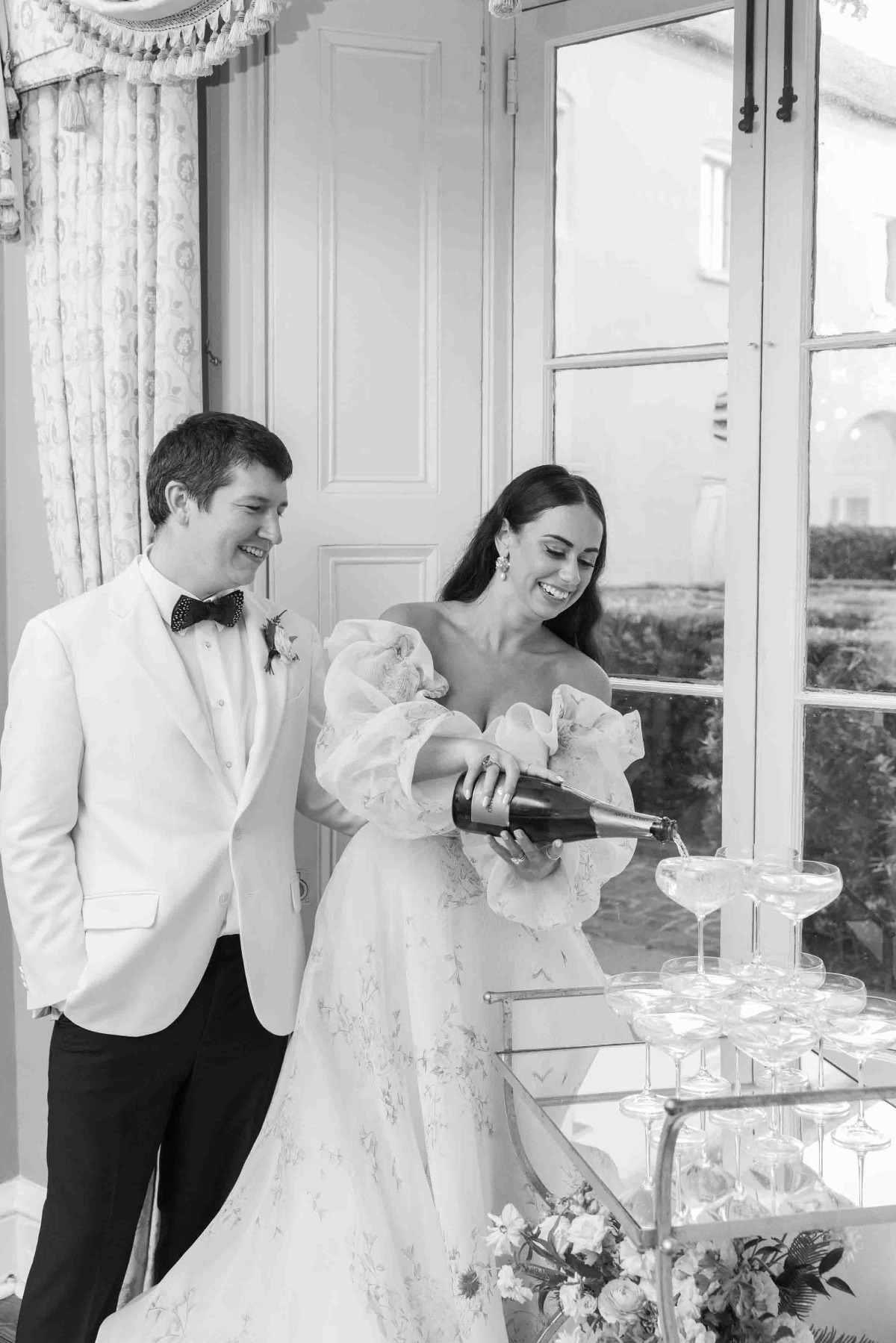 Bride in floral wedding dress pouring champagne tower 