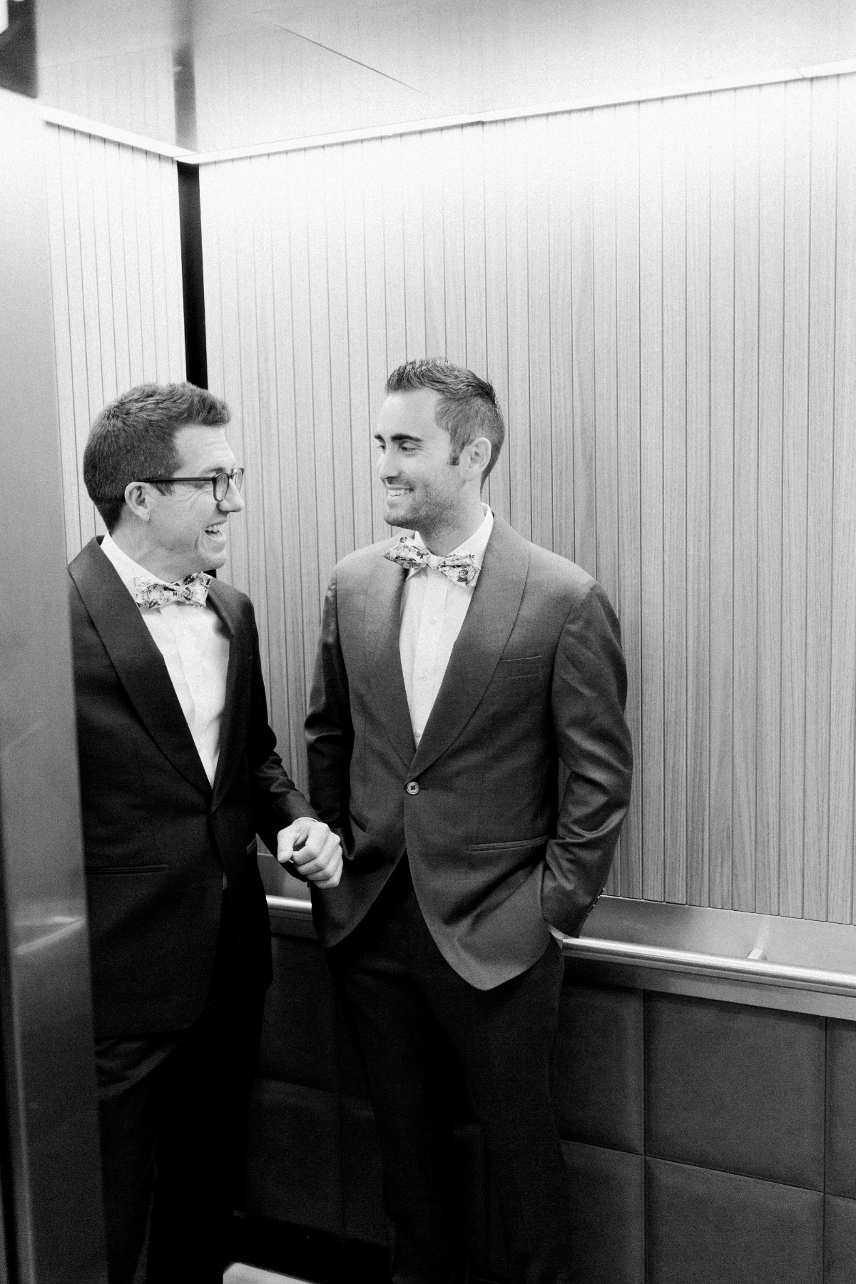 Dapper grooms in custom suits riding elevator at Clayton