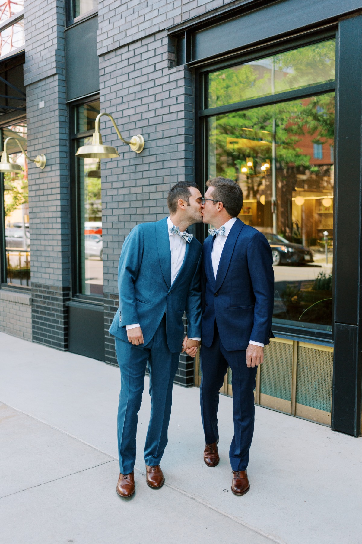 Two Denver grooms in custom suits kissing for portraits