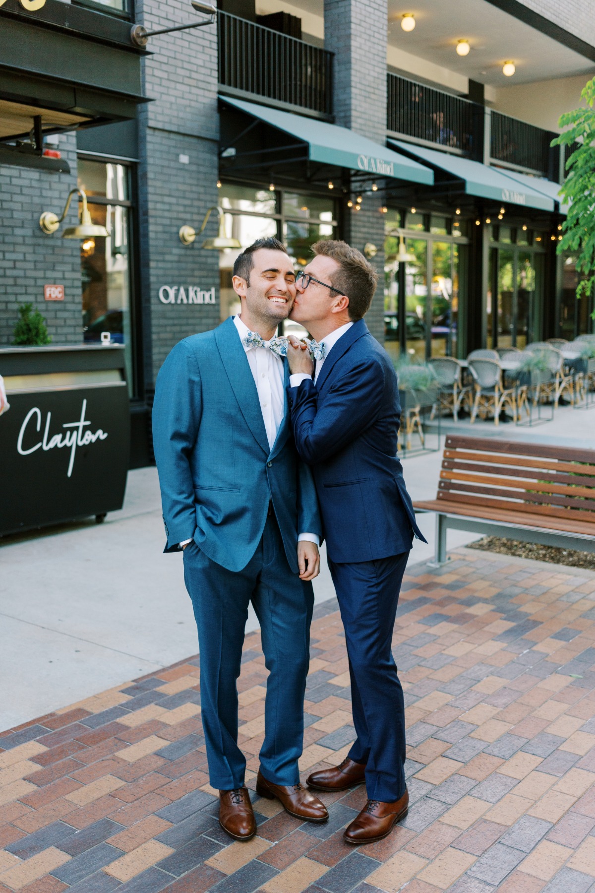 Two grooms in custom blue suits kissing for photos in Denver 