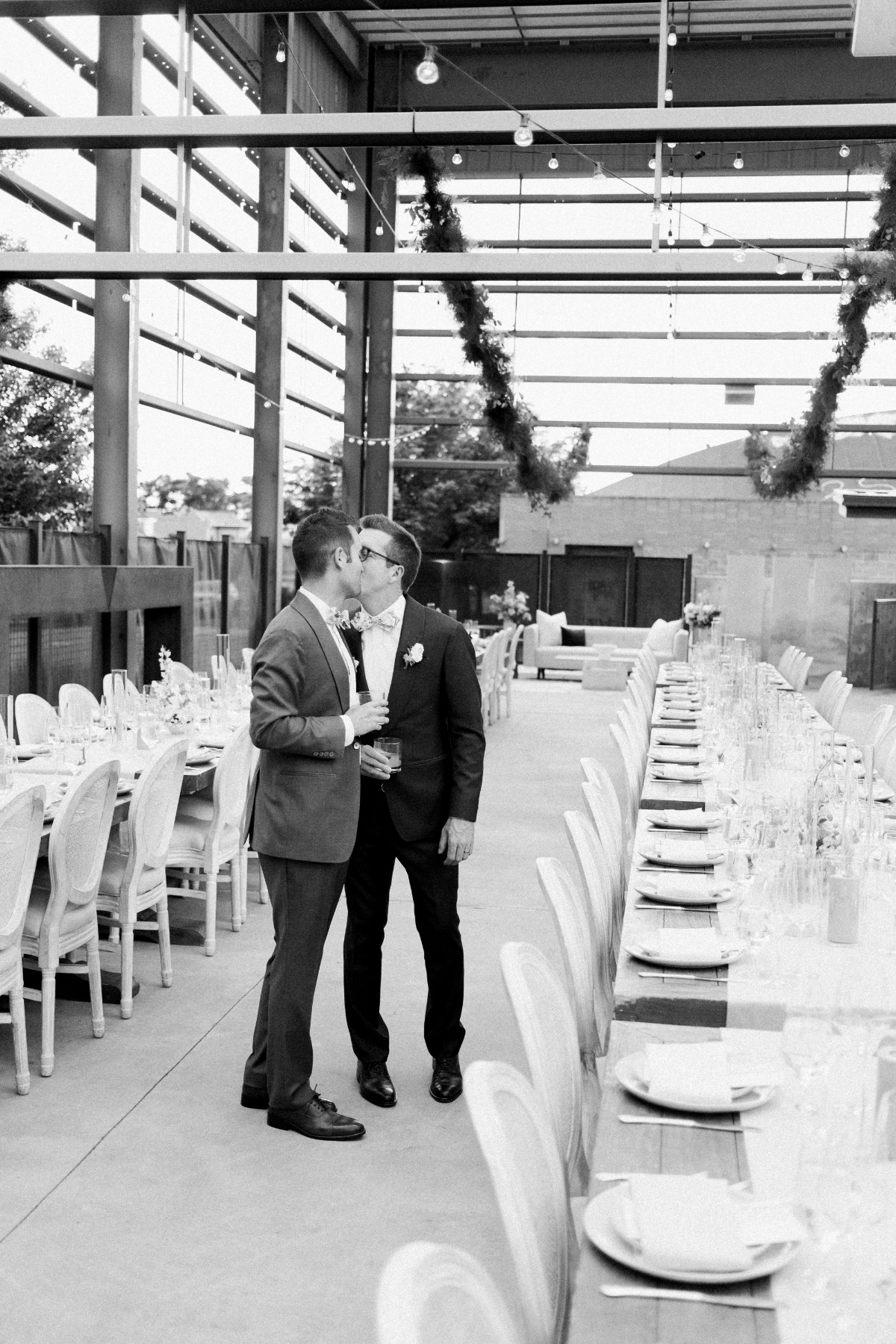 Two grooms kiss at pastel outdoor reception at Space Gallery
