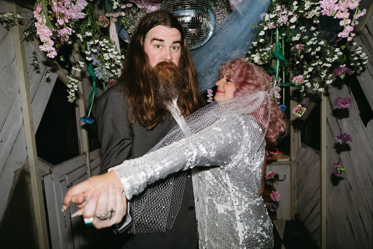 groom with long hair and bride with pink hair and sequin dress