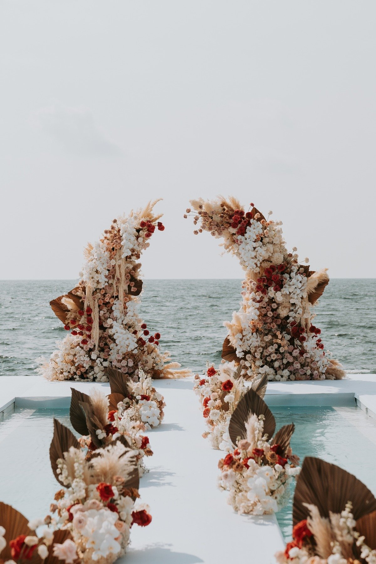 earth tone floral arch with pampas grass at beach wedding