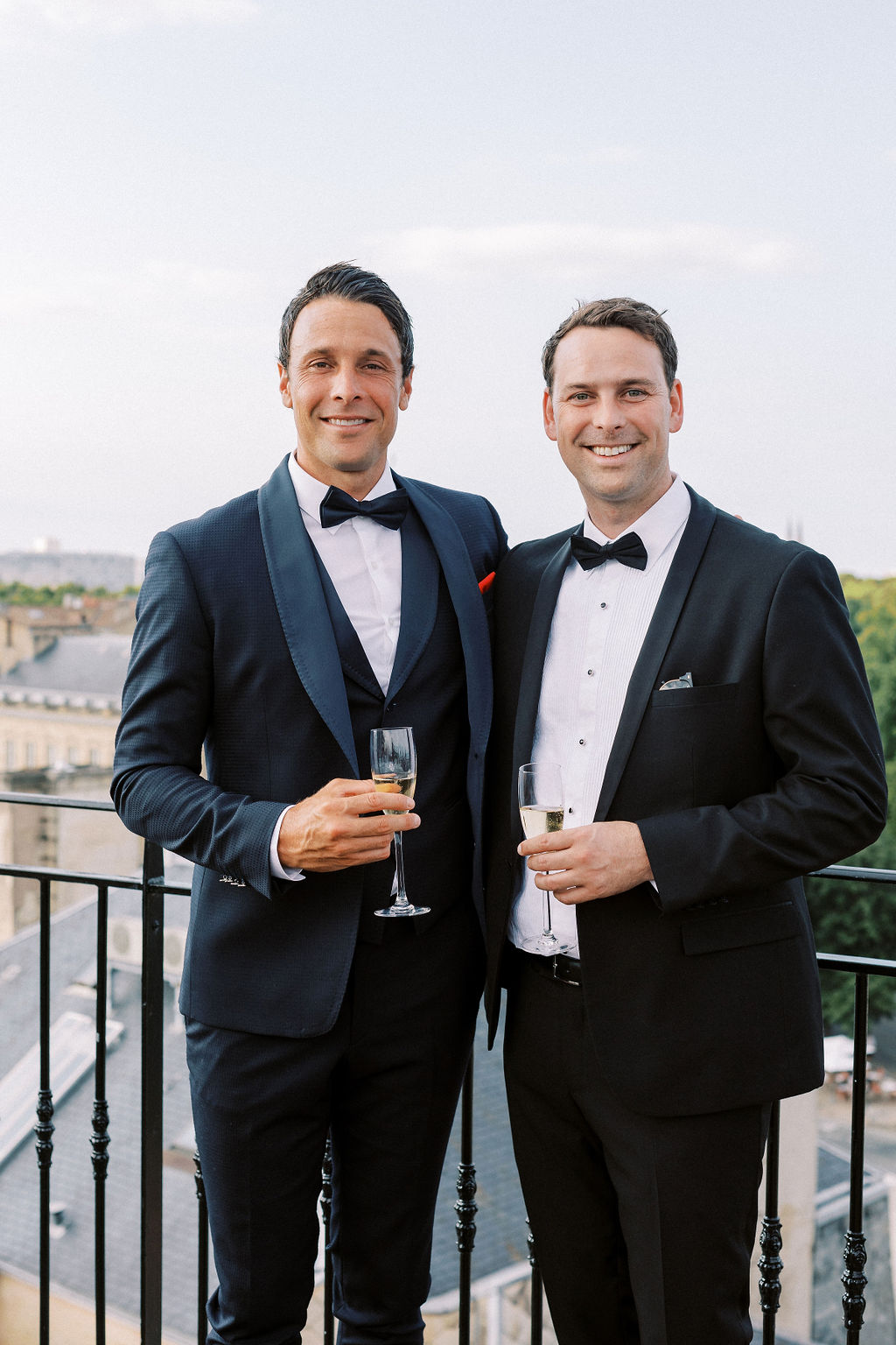 Groom and son toasting champagne on French hotel rooftop