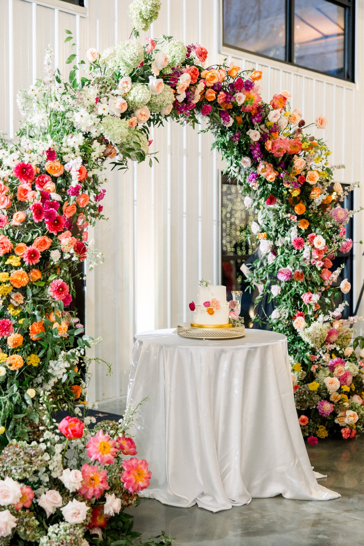colorful floral arch over wedding cake