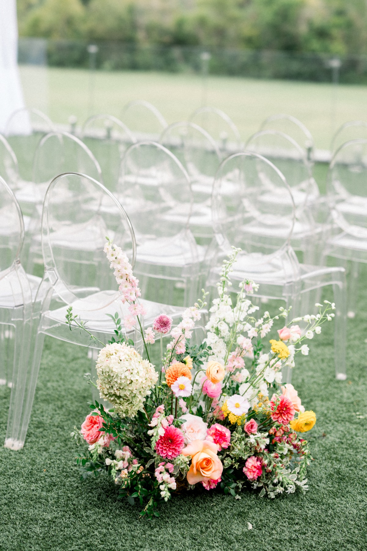 bright flowers and clear ghost chairs for wedding ceremony