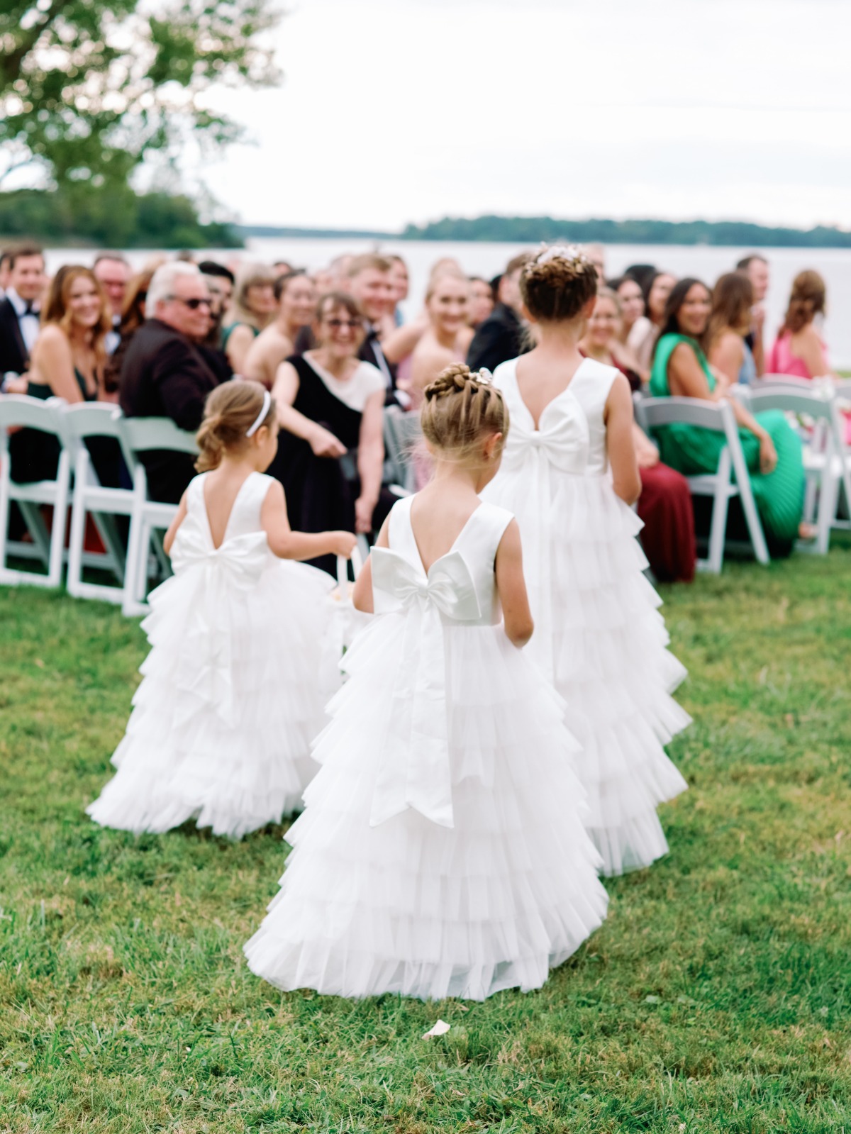 Flower girls in white dresses at an outdoor wedding ceremony