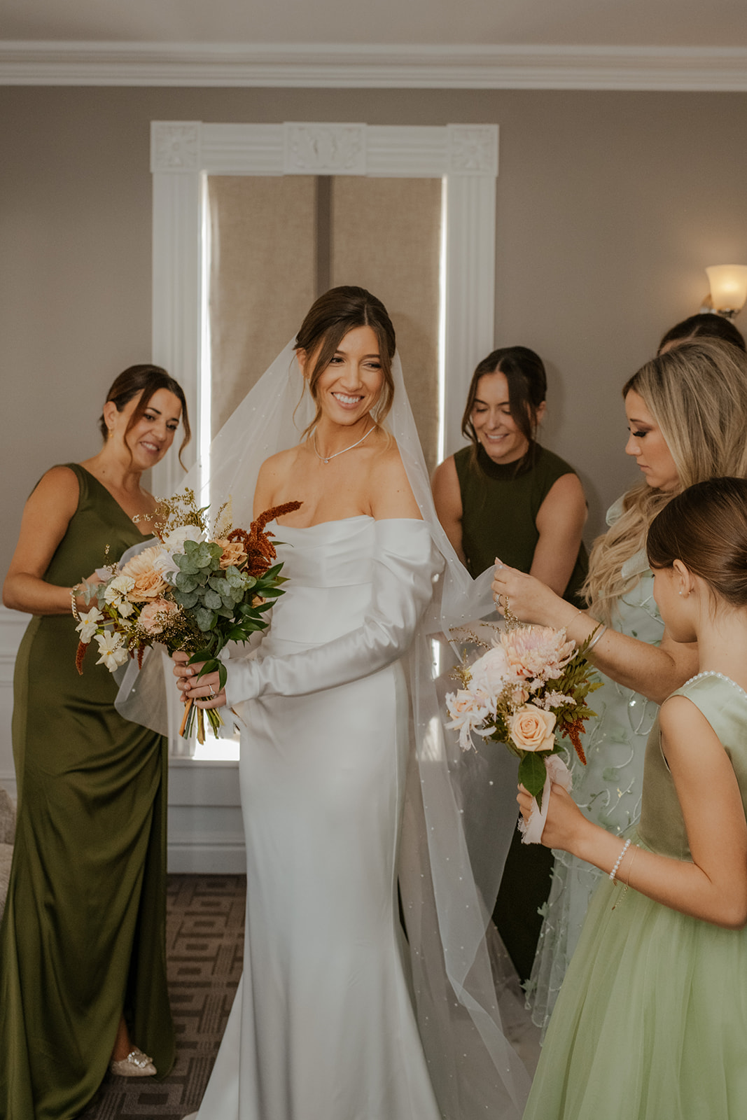 bridesmaids helping bride get into dress