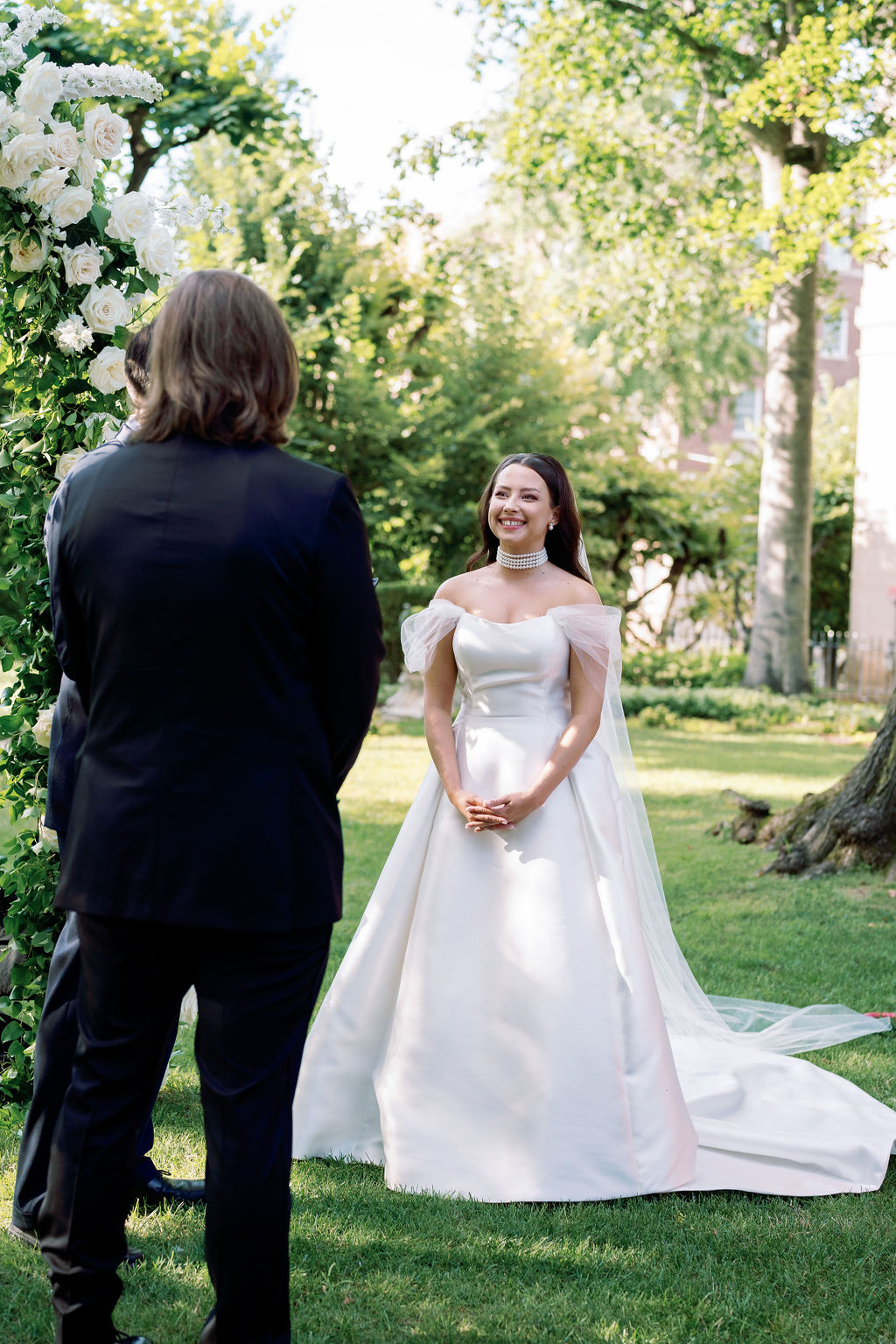 monochromatic garden wedding ceremony with white rose arch