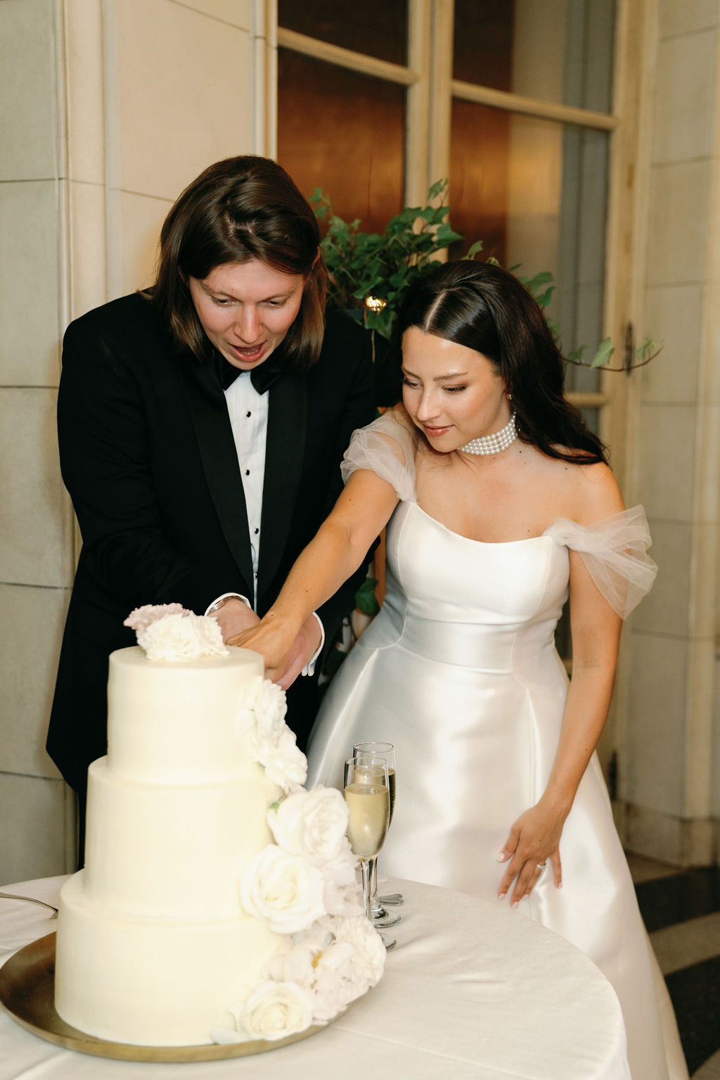 bride and groom cutting simple buttercream cake with roses