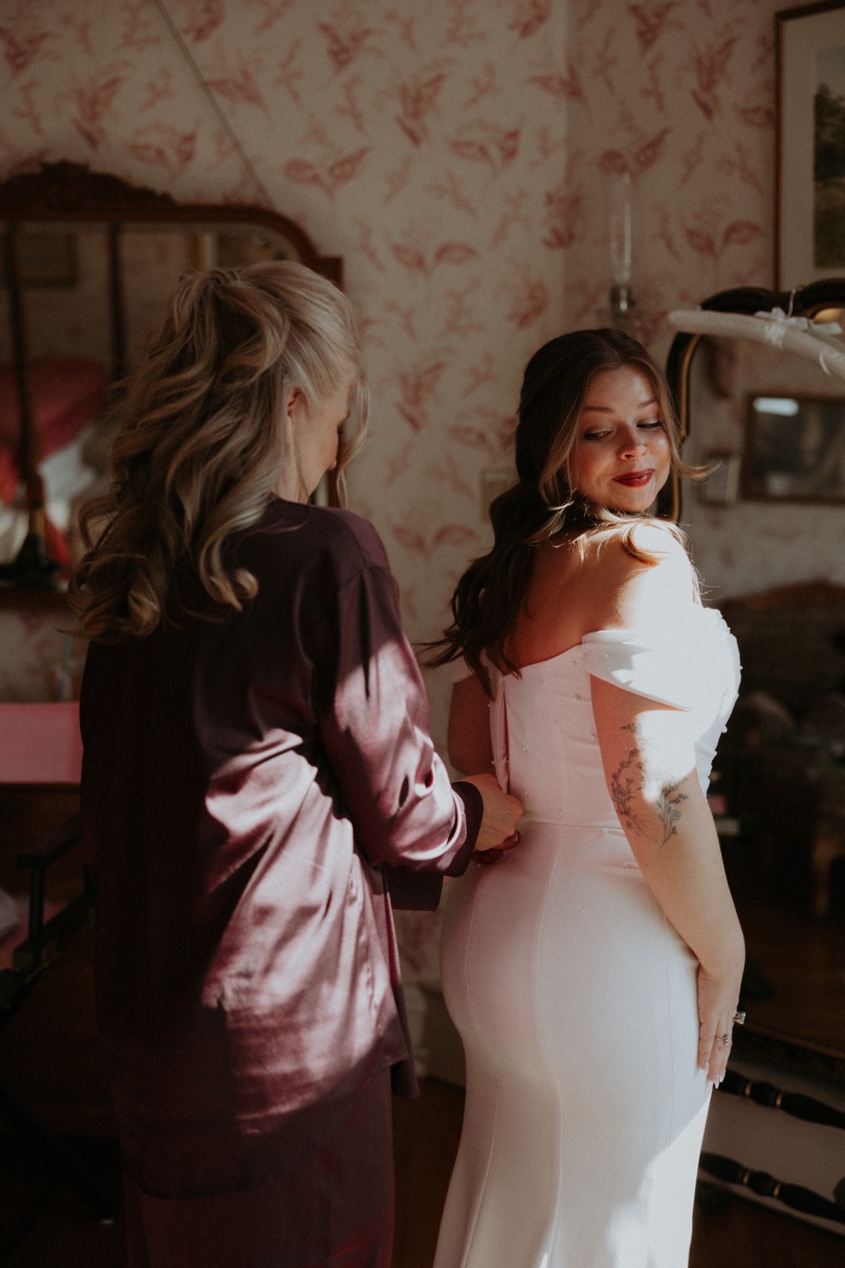 mother zipping up bride in wedding dress
