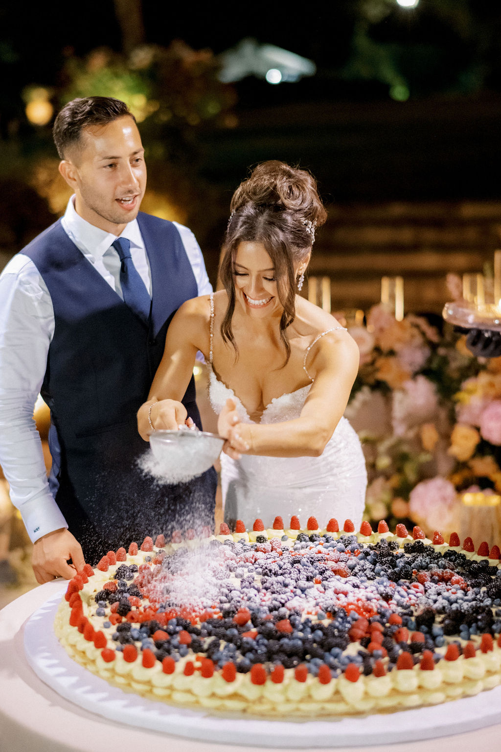 bride and groom putting sugar on italian wedding cake