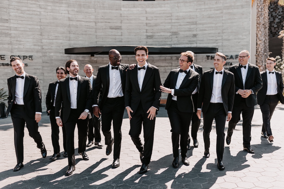 groomsmen in black tuxes walking and laughing