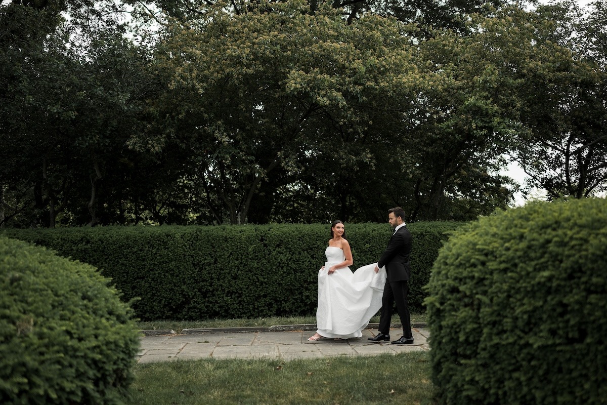 Couple walking outside next to dark green bushes