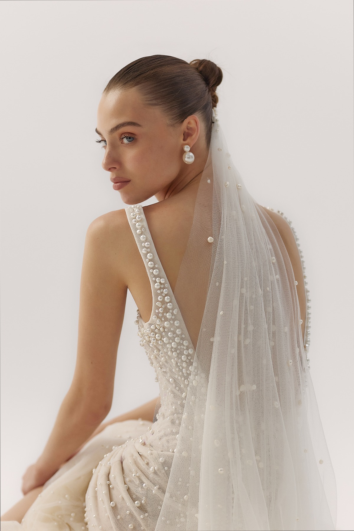 close up back shot of bride with pearled veil, earrings and dress