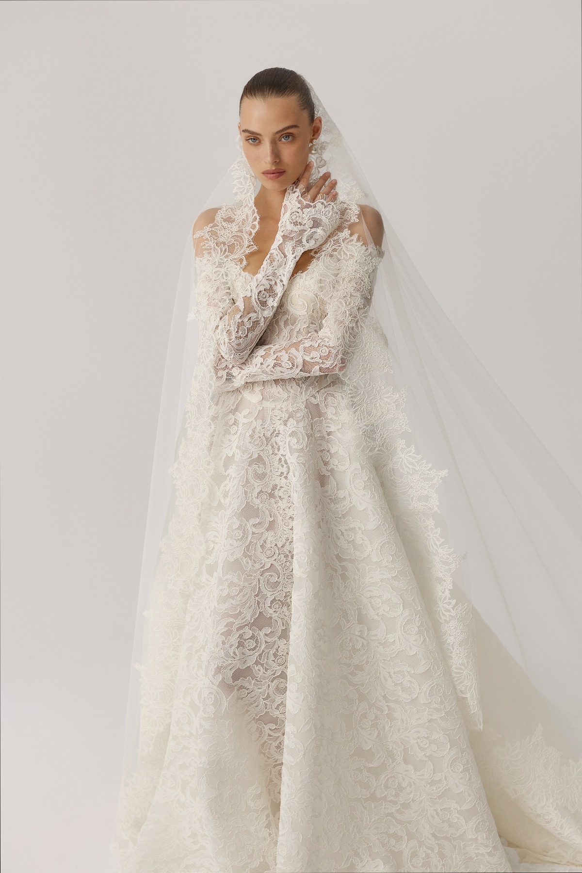 bride wearing long sleeve lace wedding gown with cathedral veil