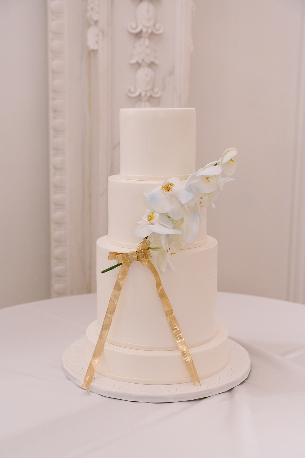 four tiered wedding cake with white fondant and orchid