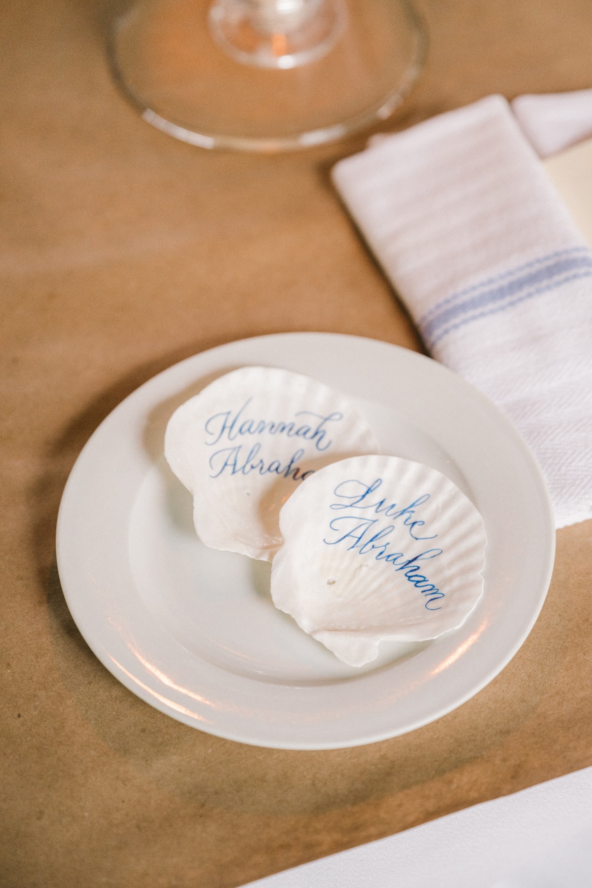 Seashells place setting name cards with white shells and blue painted names