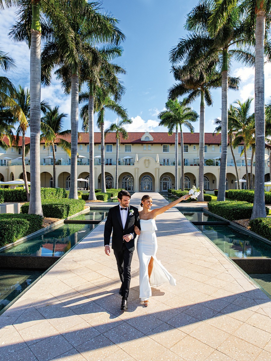 bride and groom walk down palm tree outdoor aisle