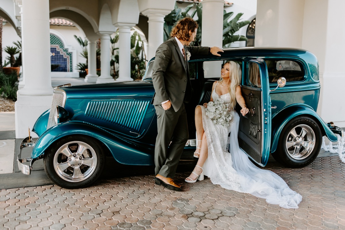 bride and groom pose with teal vintage car