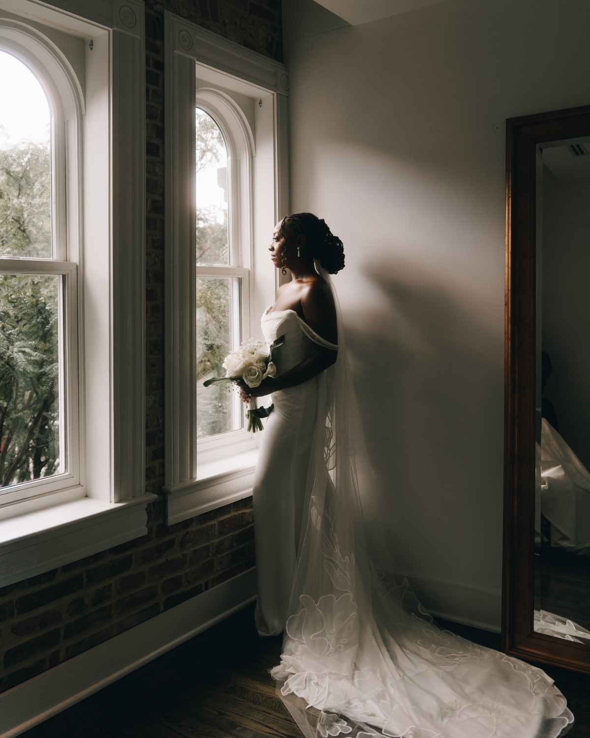 bride looking out window at historic venue