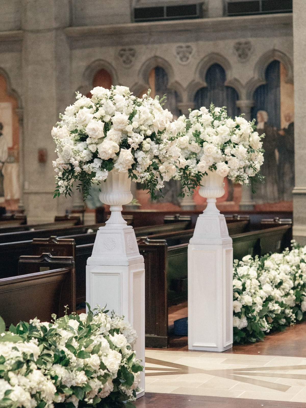 tall lush white floral arrangements on white pillars