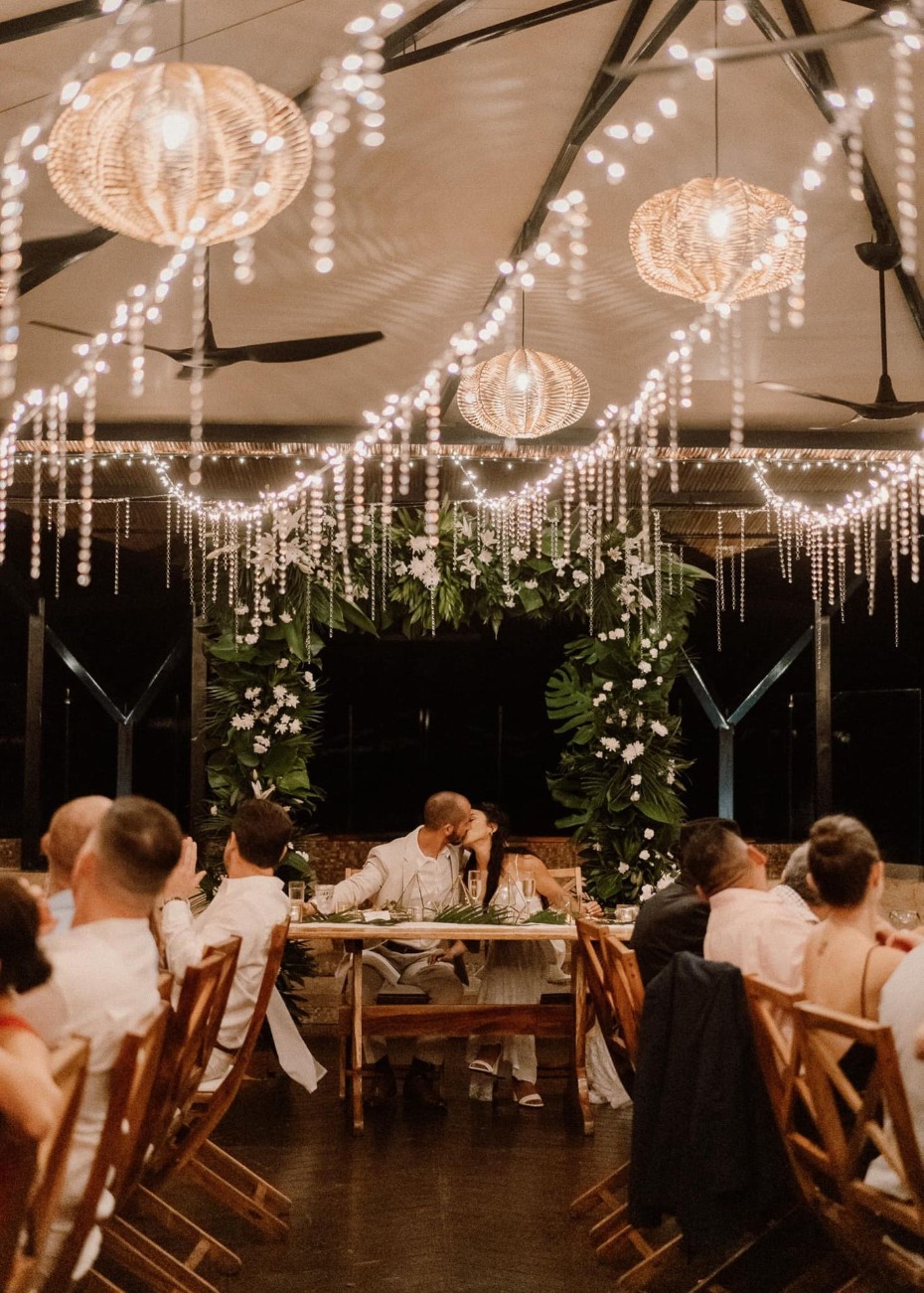 couple kissing in dark reception space with twinkle lights