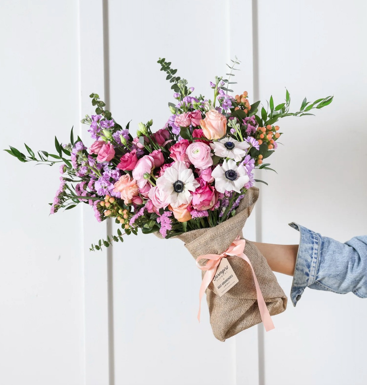 girls arm holding colorful flower bouquet wrapped in burlap