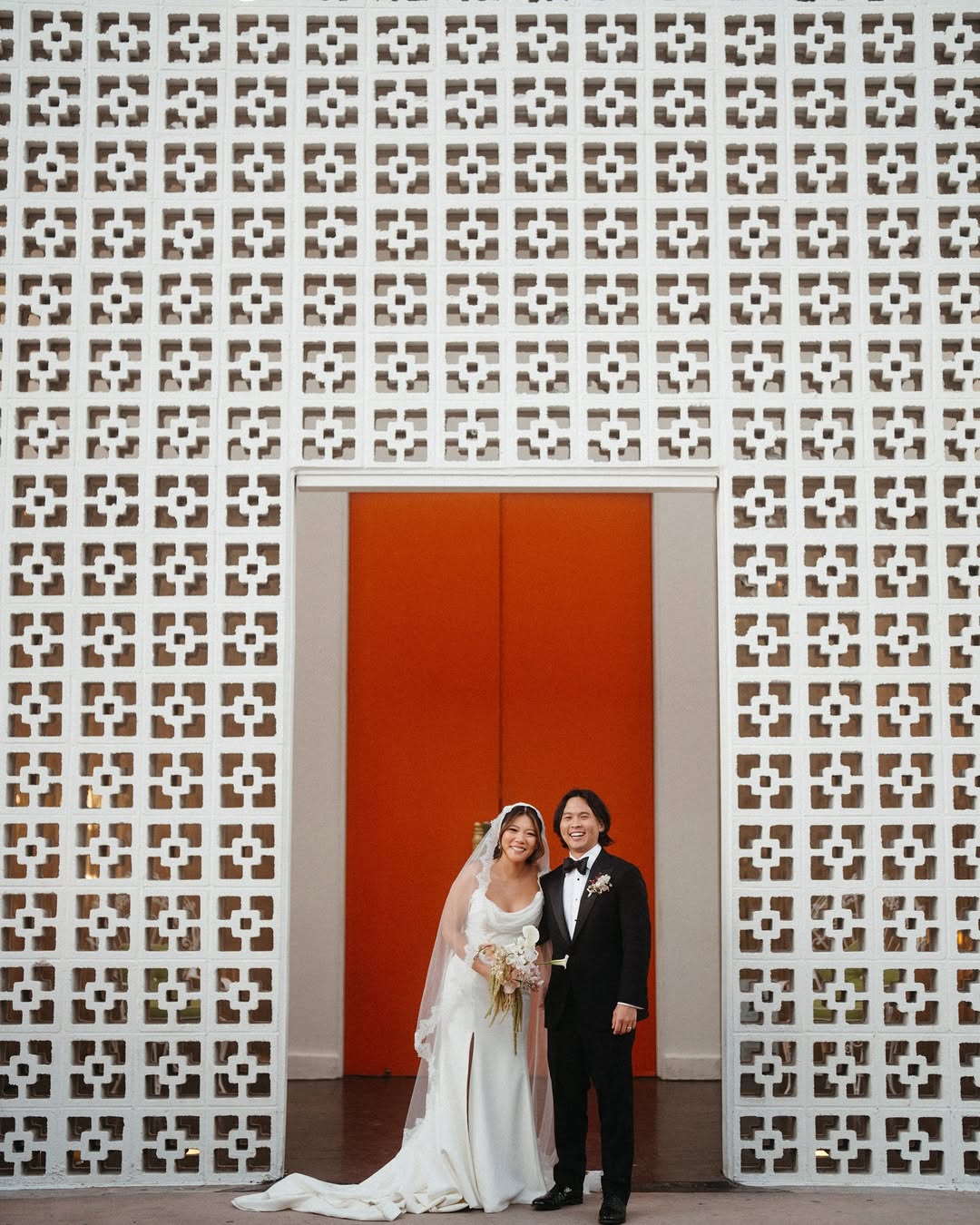 wedding couple standing in front of orange door in palm springs