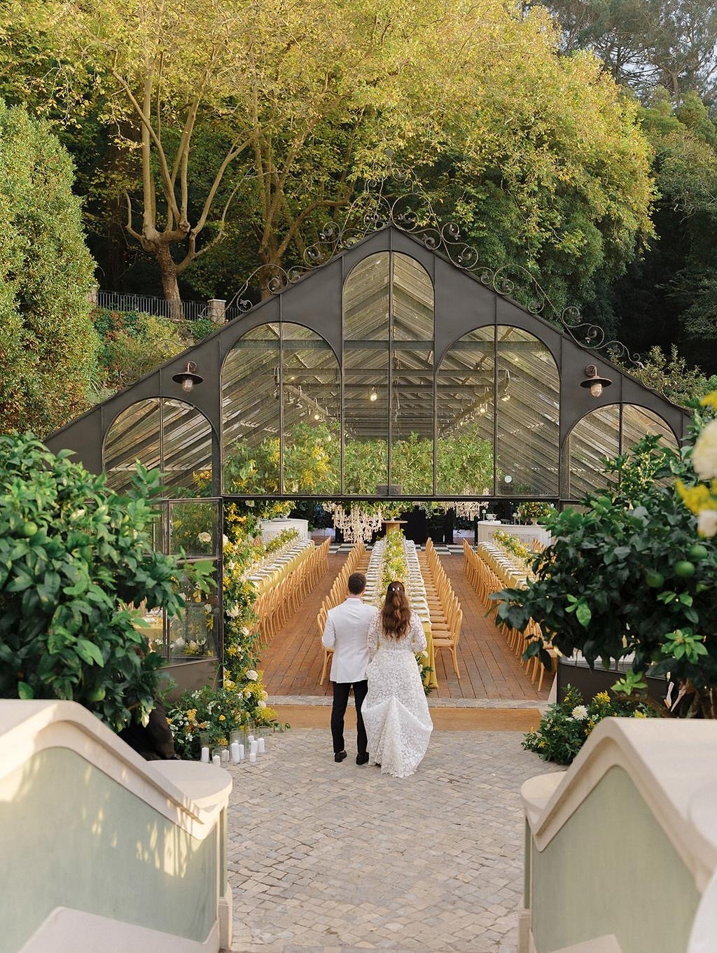 couple looking at black greenhouse wedding venue with lots of trees