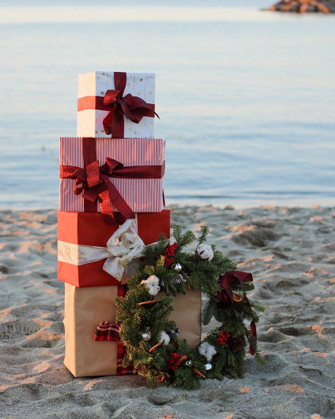 holiday gifts wrapped up on a beach with christmas wreath